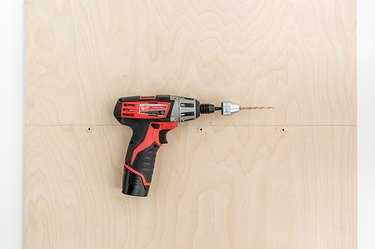 a power drill lies on a sheet of plywood