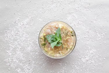 a jar of body scrub with a fresh mint leaf on top