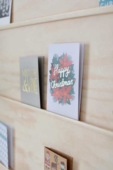 close-up on holiday cards sitting on shelves made from thin strips of moulding glued to a plywood sheet