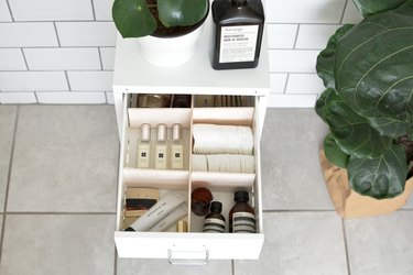 an open bathroom vanity drawer with dividers and cosmetics