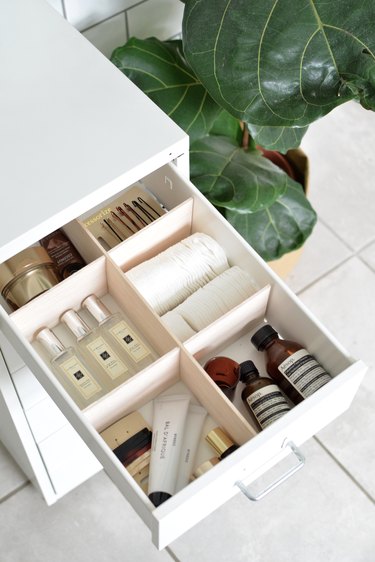 Makeup Organizer Ideas on an open bathroom vanity drawer with dividers and cosmetics