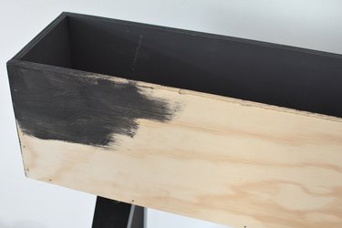 a diy wooden planter made from an ikea desk kit being painted black
