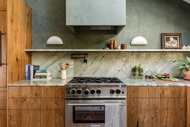 Wood cabinet kitchen with green walls and a granite or marble backsplash.