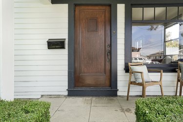 A wood door on a house with white siding