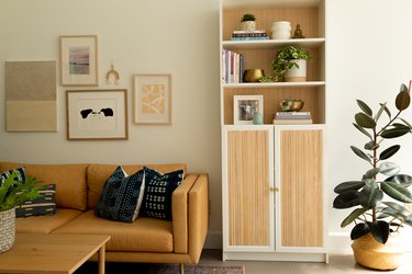 Ikea cabinet with moulding in pine cabinet doors, in a living room with blue and yellow decor and plants