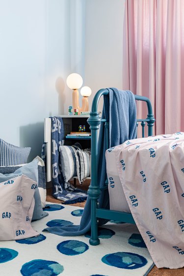 Kid's bedroom with a blue and pink theme, GAP logo bed sheets, pink curtains, and globe lamps