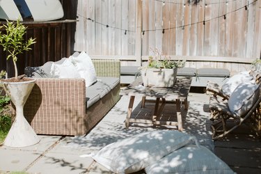 An outdoor patio with a wicker couch, two chairs, and a patio table