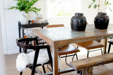 Dining room with farmhouse table, vases, bench, chairs.
