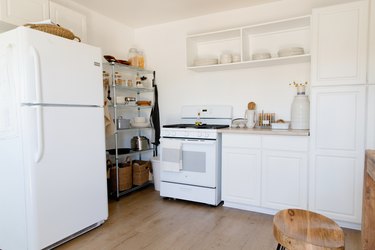 Kitchen with white cabinets, beige countertops, and metal storage rack