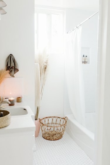 White bathroom with shower and wicker basket on floor