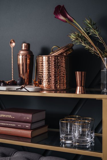 Shelving with books and glassware with copper cocktail set and flowers