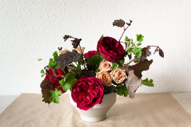 a diy floral centerpiece made of caramel roses and red flowers  including ranunculus and zinnias