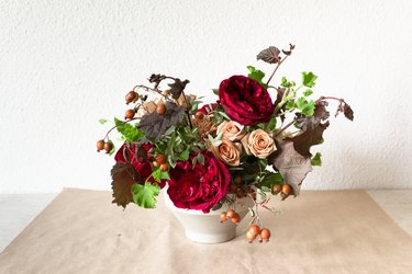 a diy floral centerpiece made of caramel roses and red flowers  including ranunculus and zinnias