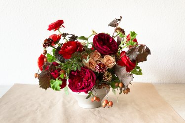 a diy floral centerpiece made of caramel roses and red flowers  including ranunculus and zinnias