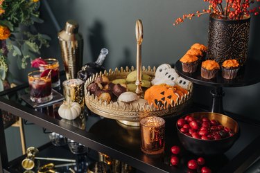 Gold cake stand with Halloween cookies and autumnal flowers and pumpkin decor