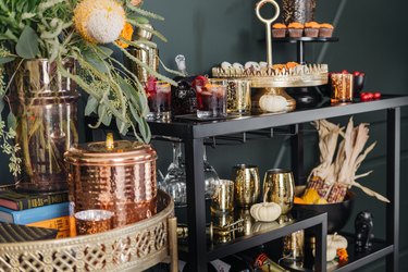 Bar cart with gold cocktail set, autumnal flowers, pumpkins, and corn