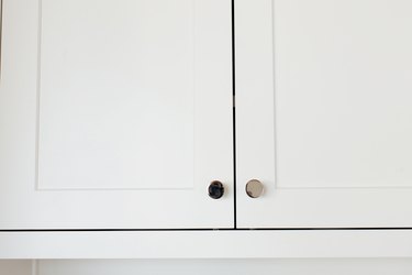 Closeup of white cabinet doors with chrome knobs.