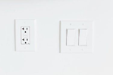 Double light switch and an outlet on a white wall.