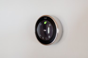 A Nest thermostat on a white wall.