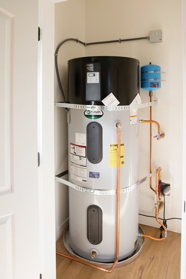 A water heater in a small white room.