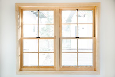 Double windows with light-wood frame on a white wall