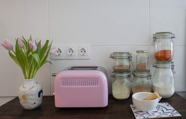 pink toaster and glass jars on wooden kitchen countertop