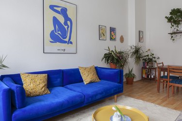 blue velvet sofa with mustard gold accents and modern abstract art