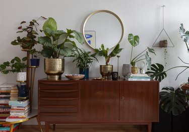 midcentuy credenza in living room with boho plants and round gold mirror