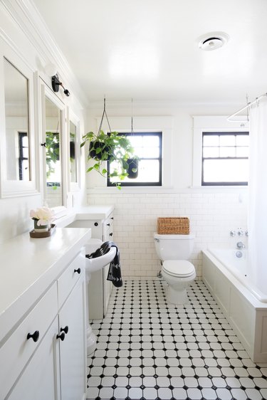 White walled bathroom with hanging plant and white-black tiled floor