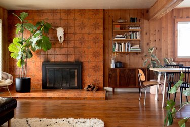 Southwest living room with animal skull, brown floral fireplace, wood panel walls, wood bookshelves and eclectic furniture