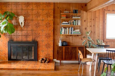 Southwest living room with animal skull, brown floral fireplace, wood panel walls, wood bookshelves and eclectic furniture