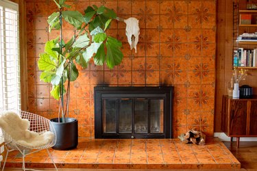 Southwest living room with an animal skull, floral terra-cotta fireplace, fig tree plant, white modern chair and sheep throw