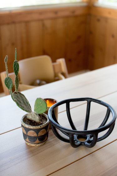 table with potted paddle cactus, empty fruit bowl, and illuminated candle