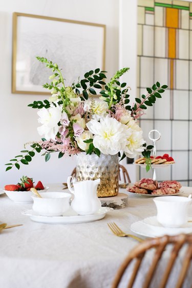 Dining table with flowers, china dishware in dining room with stained glass window