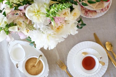 White and pink flowers with white china and gold utensils