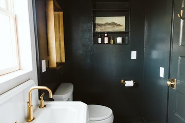 small bathroom wall art on black walls near mirror with brass frame