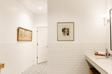 White tiled bathroom walls with framed fruit print and floral floor tiles.