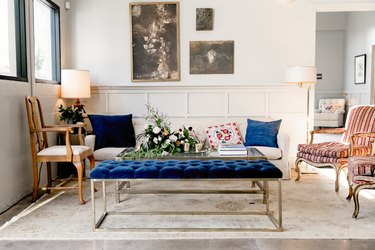 Sitting area with striped fabric and wood chairs and blue velvet chesterfield bench