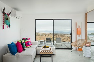 Minimal desert-inspired living room with light gray couch and neon geometric throw pillows