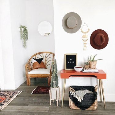 White-dominant southwestern-inspired entryway with rattan armchair and orange midcentury console