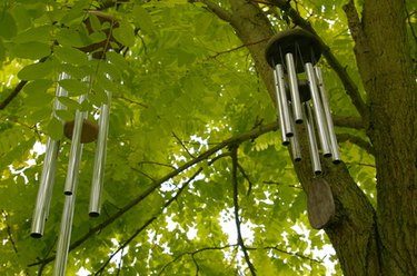Metal wind chimes hanging  from tree branch.