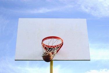 Low angle of a basketball going through the net.