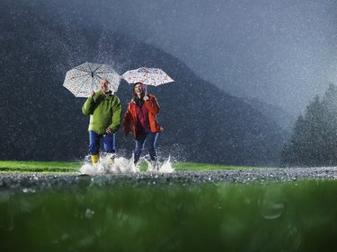 Man and woman with umbrellas playing in the rain.