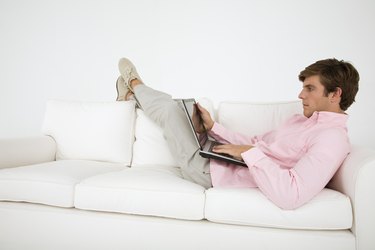 Man lying on sofa with laptop computer