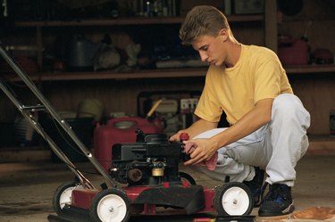 Teenage boy fixing lawnmower