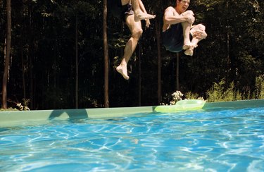 People jumping into a swimming pool.
