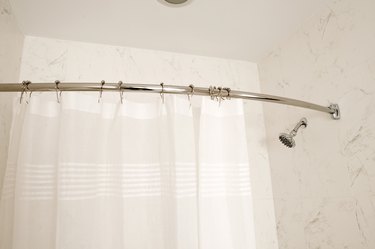 Curved shower rod, white bathroom and shower curtain.