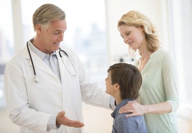 Doctor Explaining Boy While Mother Looking At Him In Clinic