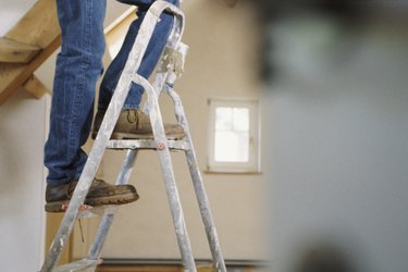 Man standing on step ladders, legs only