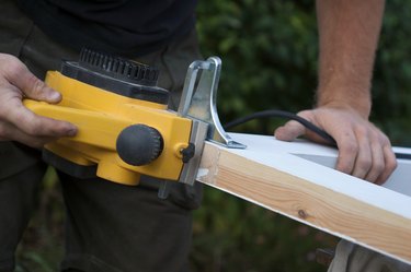 Carpenter using an electric planing tool on a door frame